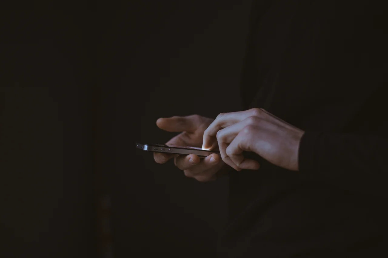 Dark visual of hands working on a phone