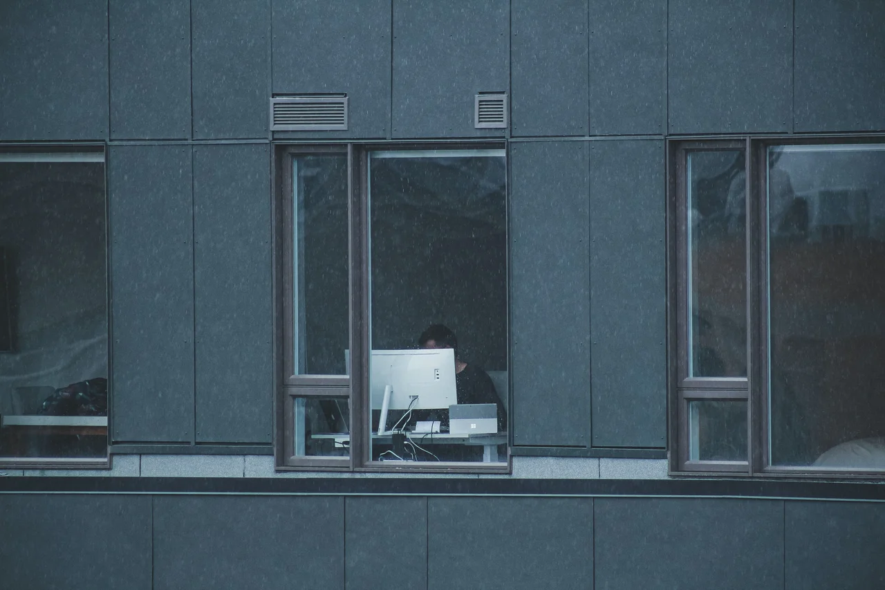 Person working on a computer (through a window)
