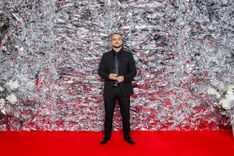 Man in a suit standing in front of a silver photo wall
